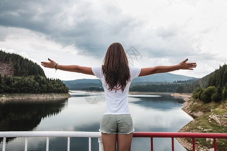 克罗地亚湖边安全栅栏前张开手臂的女人图片