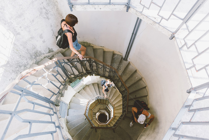 三名青年成人从螺旋楼梯下行的高角度视意大利隆巴迪科莫图片