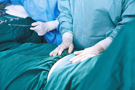 外科医生把手放在病人的腹部图片
