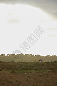 雄山骑自行车在荒地上骑自行车的远视图片