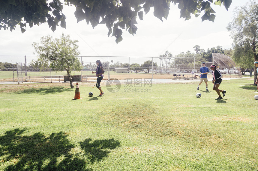 在学校操场与女学生一起踢足球的男教师图片