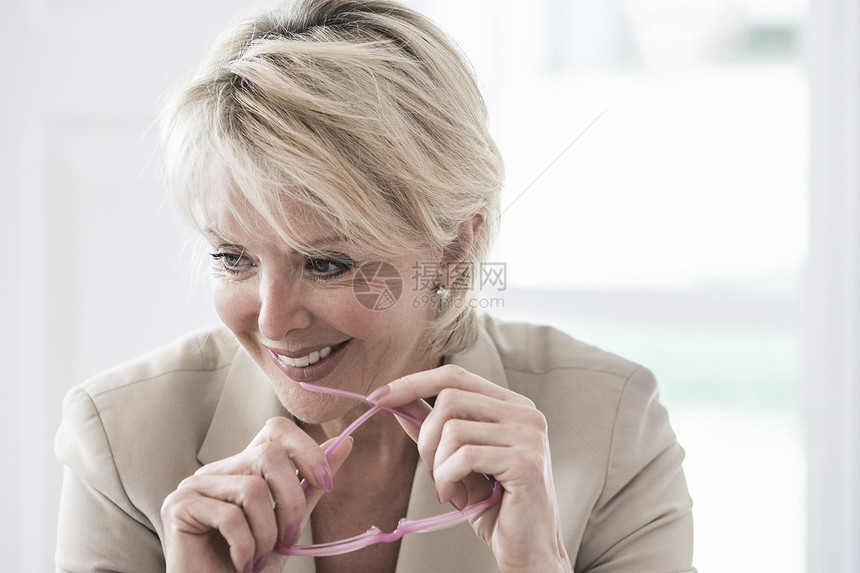 女人拿着眼镜微笑着向下看图片