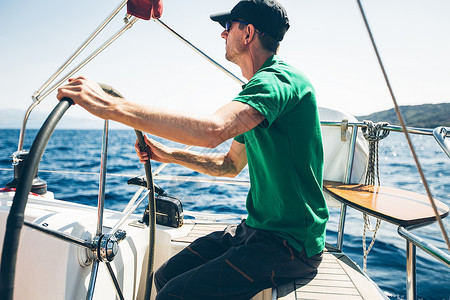 克罗地亚海岸附近驾驶游艇的中成年人男子高清图片