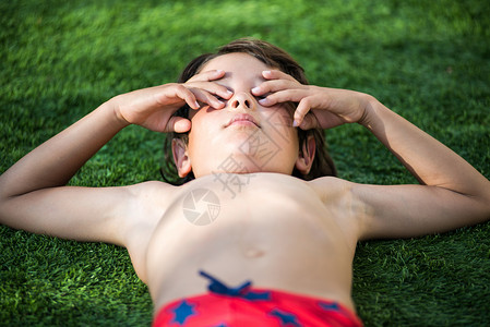 男孩躺在草地上遮着眼睛图片
