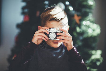 男孩拍照圣诞树背景图片