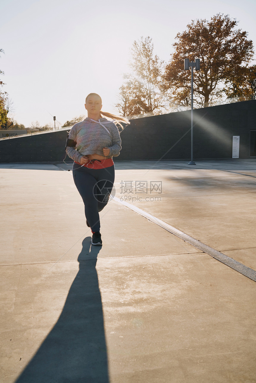 在阳光下奔跑的游荡年轻女跑者图片