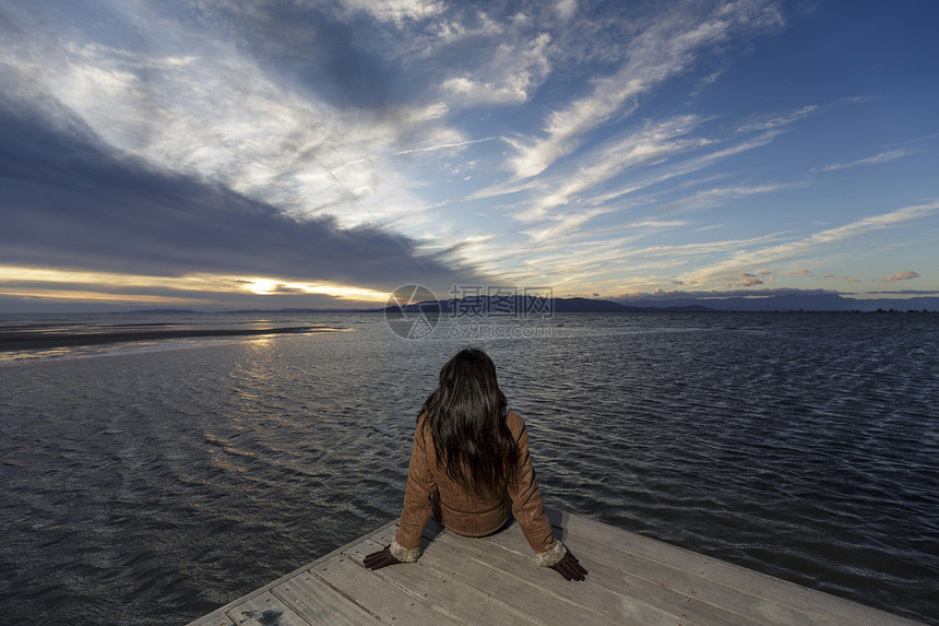 西班牙加泰罗尼亚塔拉戈纳日落时分从码头向外眺望的年轻女子图片