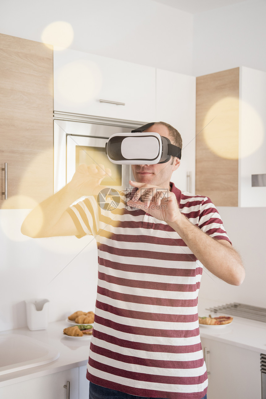 在厨房通过虚拟现实耳机看年长男子图片