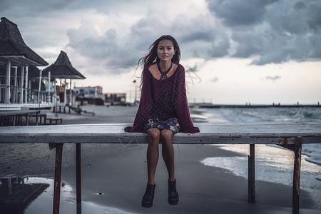 坐在乌克兰敖德萨州黄昏码头的年轻女子肖像图片