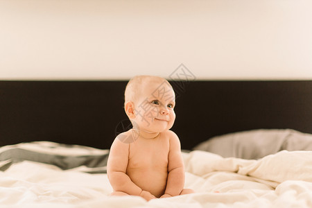 坐在床上的可爱女婴儿看向远方背景图片