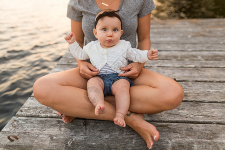 在码头女婴坐在母亲的大腿上高清图片