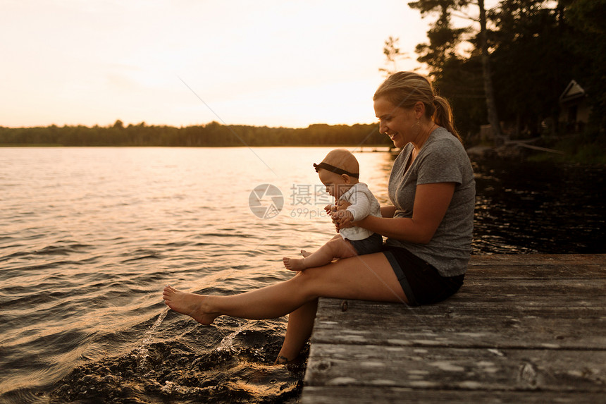 母亲和女婴坐在码头上玩水图片