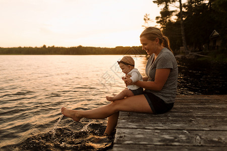 母亲和女婴坐在码头上玩水高清图片