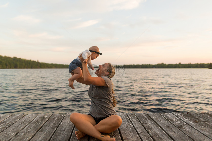 母亲盘腿坐在码头上抱着女儿图片