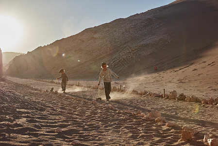 一对兄弟在智利阿塔卡马的沙漠道路上拉着玩具卡车图片