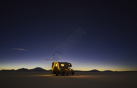 在黄昏穿过盐滩的亮着灯的车图片