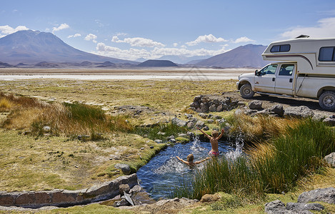 两个男孩在停泊的娱乐车旁水池玩耍i玻利维亚南美洲高清图片