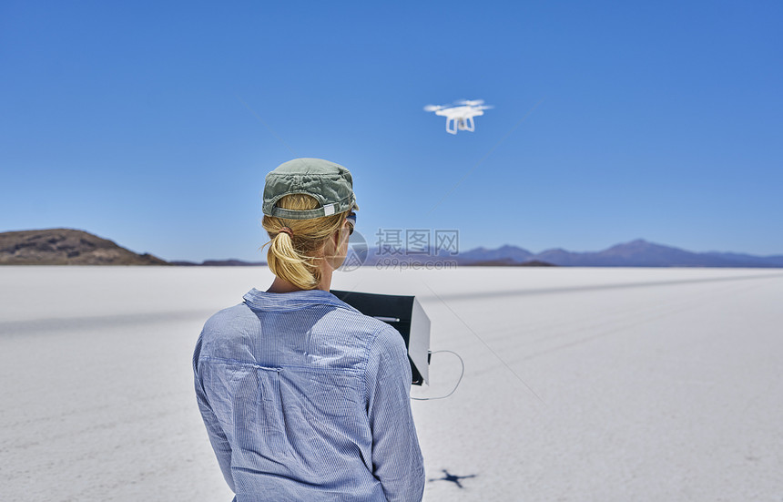 妇女在盐滩驾驶无人机的背影图片