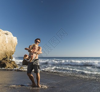 哥哥抱着弟弟大笑美国马里布塔多尔海滩高清图片