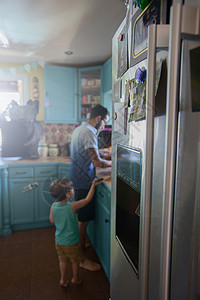在厨房柜台站父亲后面的男孩背景图片