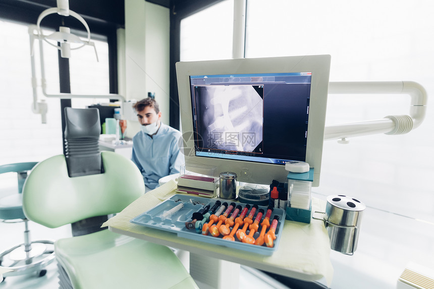 医生站在计算机屏幕上的牙科X光后图片