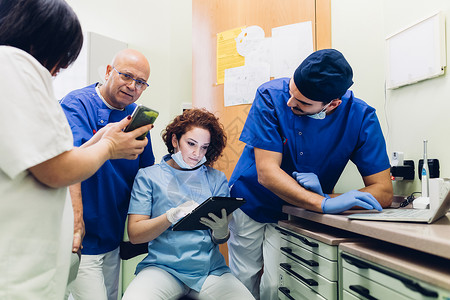 牙科办公室医看平板电脑和手机的医生们图片