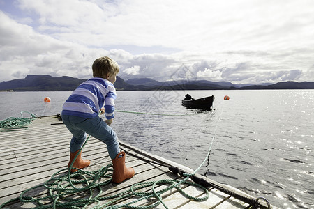 在码头上用绳索拉渡船的男孩挪威奥雷罗姆斯达尔图片