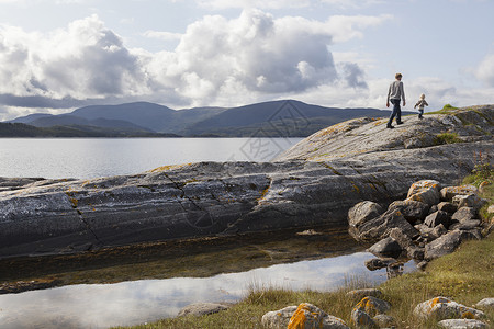 曹斯达尔人类和儿子在挪威的岩层上行走背景