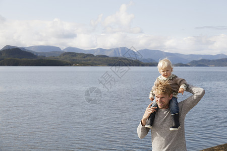 在挪威福德奥雷罗姆斯达尔湖边肩上架着儿子的男人图片