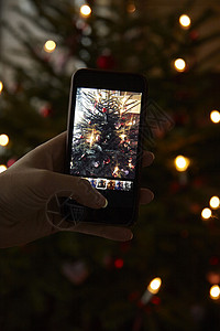 拿着手机拍圣诞树照片图片