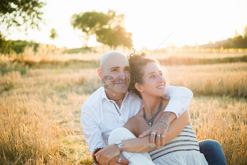 坐在田里拥抱的一对夫妇图片