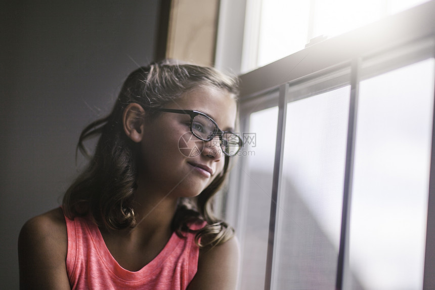 年轻女孩戴眼镜向窗外看图片