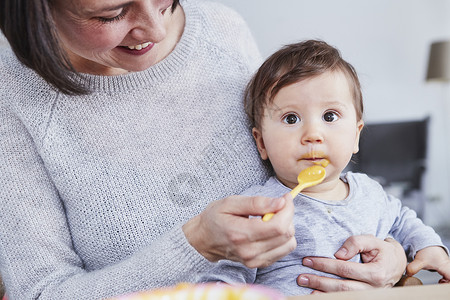母亲用勺子喂女婴吃饭图片
