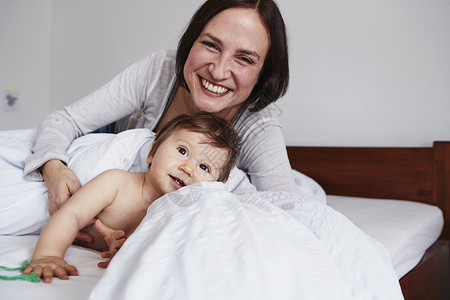 母亲和女婴在床上放松微笑图片