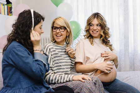 孕妇和沙发上的朋友用心率检测仪听婴儿心跳图片