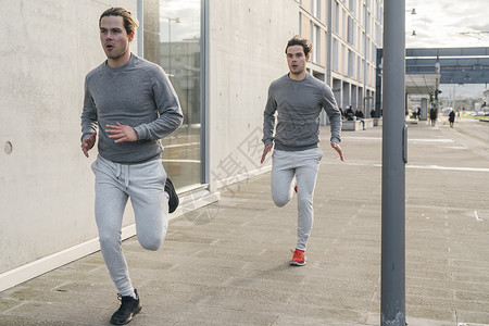 孪生兄弟年轻男双胞胎对沿城市人行道跑步背景