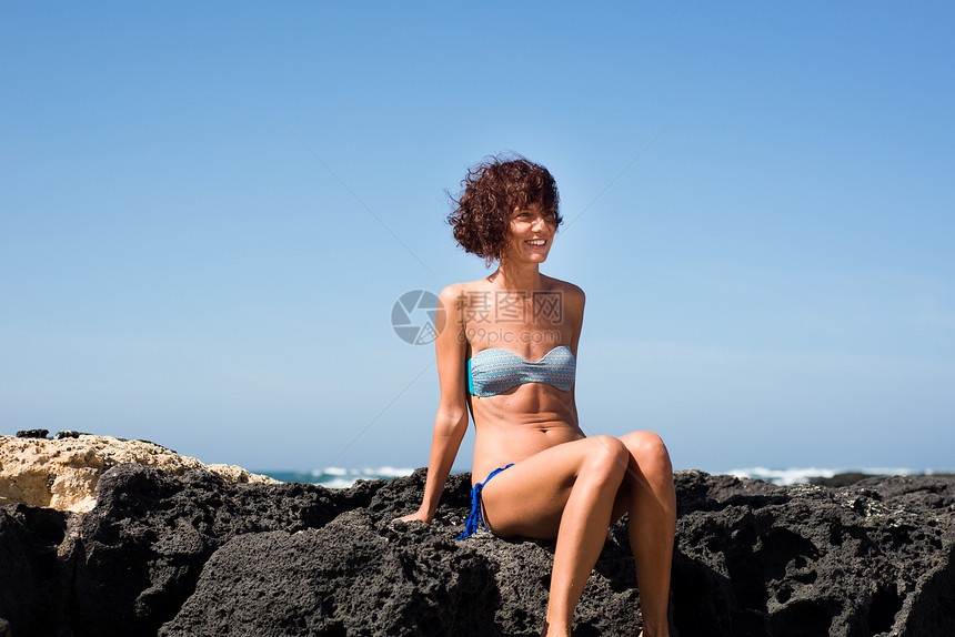 海边坐在岩石上的女人图片