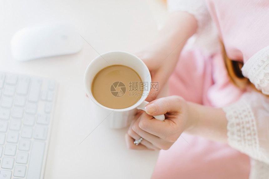 坐在电脑上拿着咖啡杯的年轻女士图片