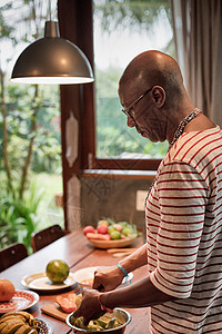 厨房餐桌上在碗里放水果的成熟男子图片