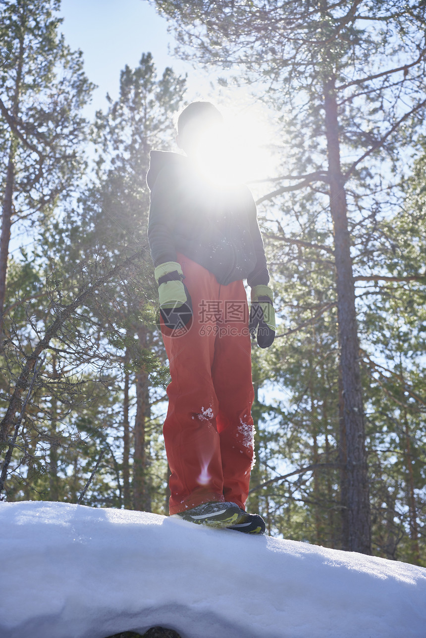 被阳光遮盖面部的年轻男孩站在雪地上图片