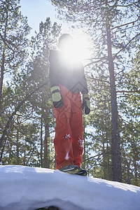 被阳光遮盖面部的年轻男孩站在雪地上图片
