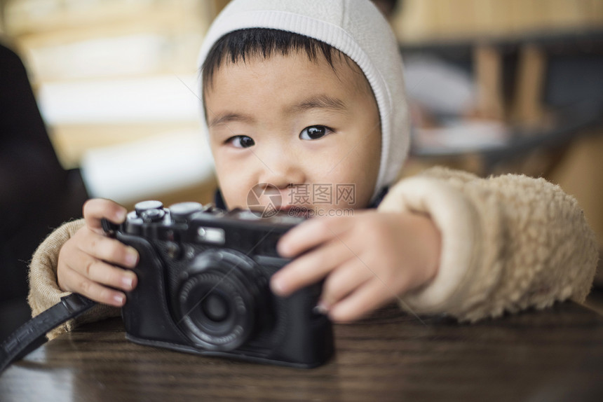 小男孩拿着相机在桌子上图片