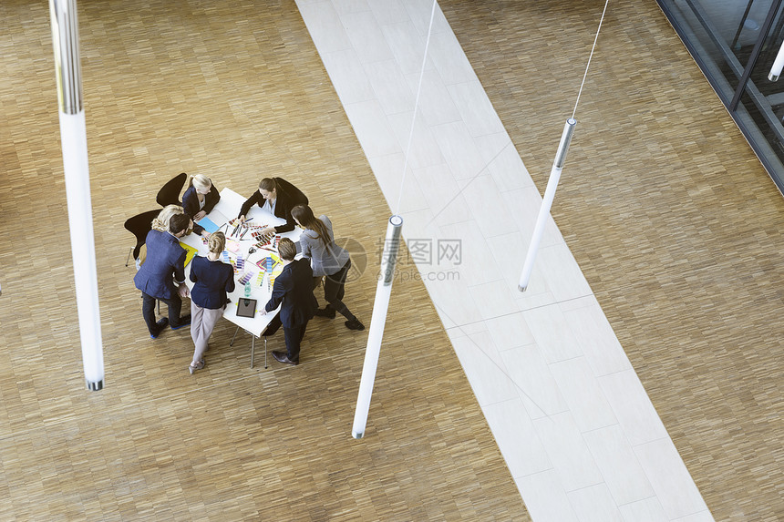 男女商人在办公室大厅里观看桌子上设计的高角度视图图片