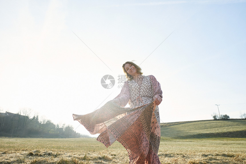 嬉皮风格的女人在阳光下田里跳舞的肖像图片