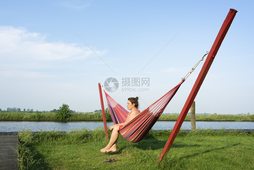 荷兰弗里斯布罗克河边吊床上放松的妇女图片