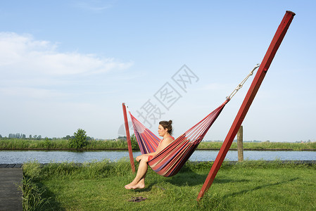 荷兰弗里斯布罗克河边吊床上放松的妇女图片