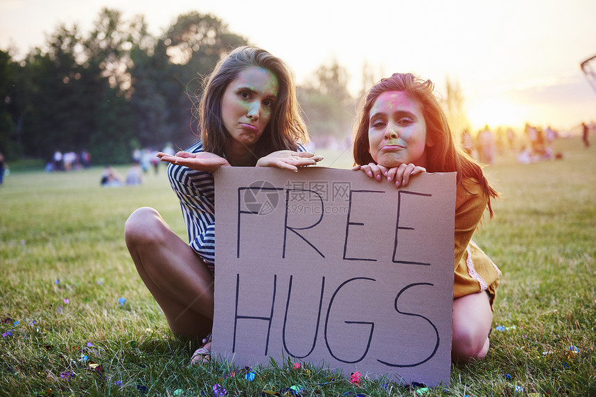 坐在草地上拿着自由拥抱的年轻女子图片