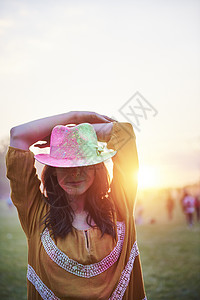 在音乐节满身彩粉手放在头上的年轻女子图片