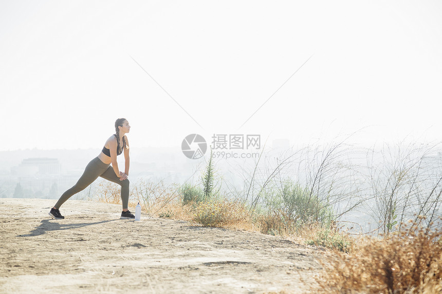 妇女在山顶上做伸展运动图片