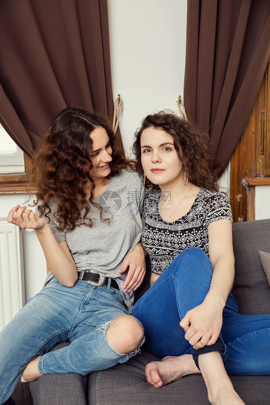 坐在沙发肖像上的两个年轻女朋友图片